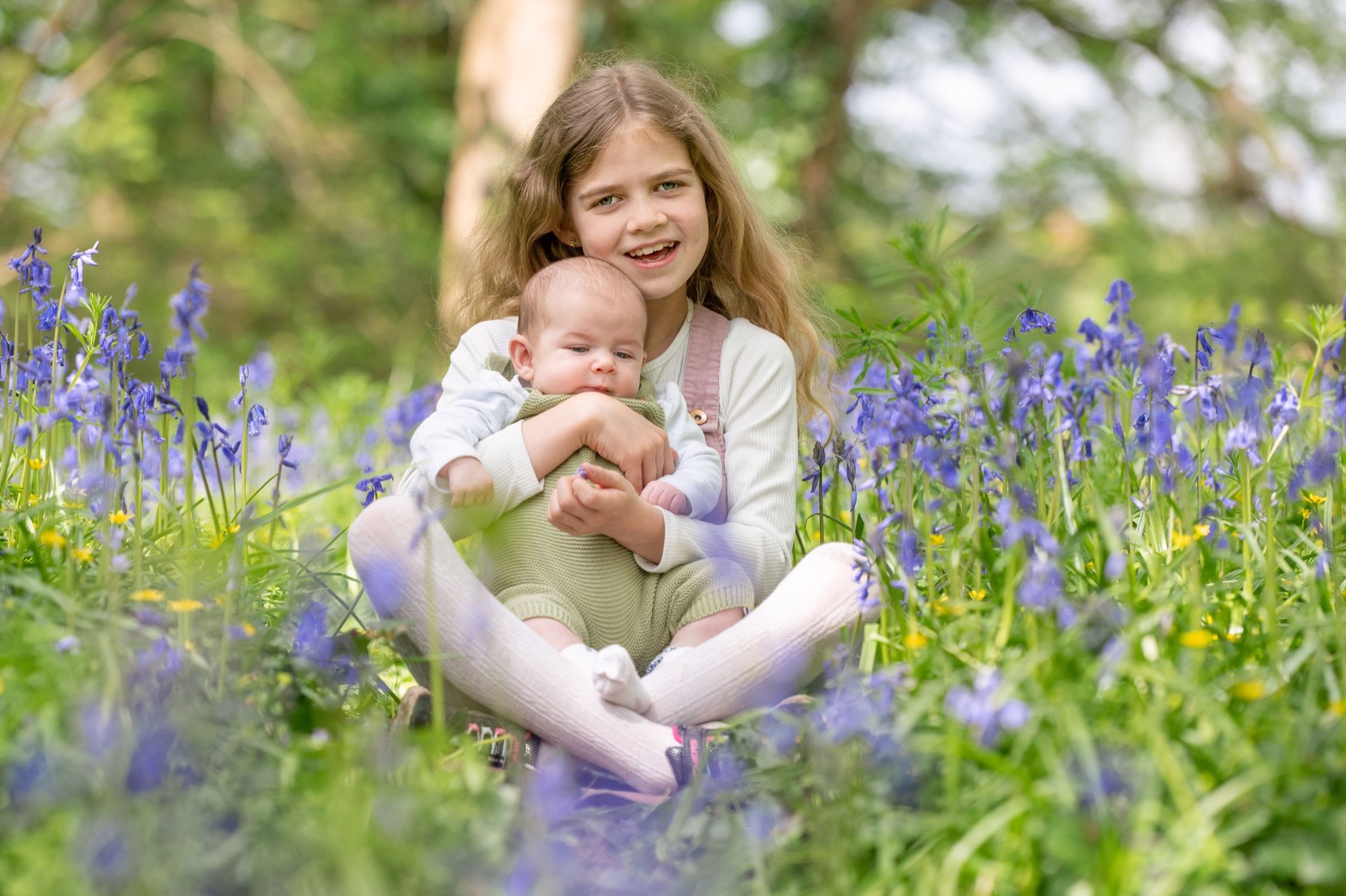 Children sitting together in bluebells during an outdoor family photoshoot