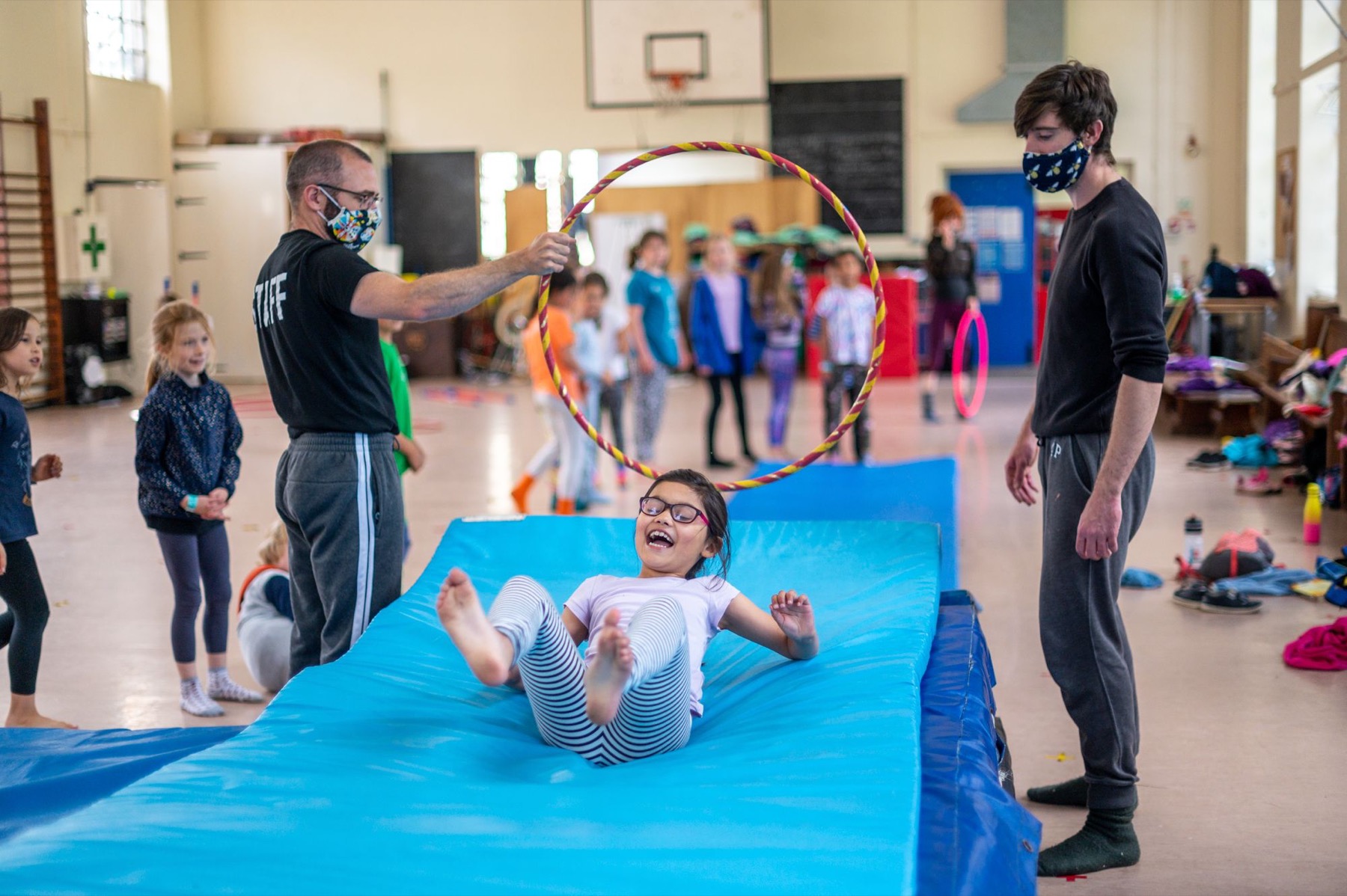 Child sliding through a circus skills hoop during an event