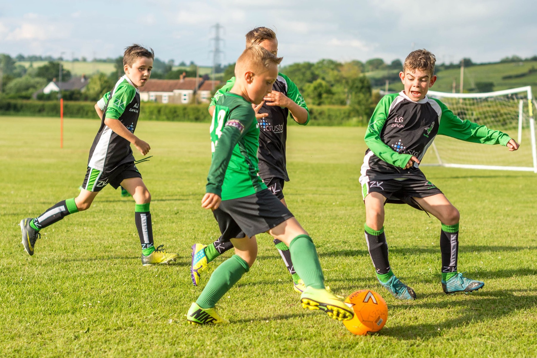 Children playing football on a sunny pitch